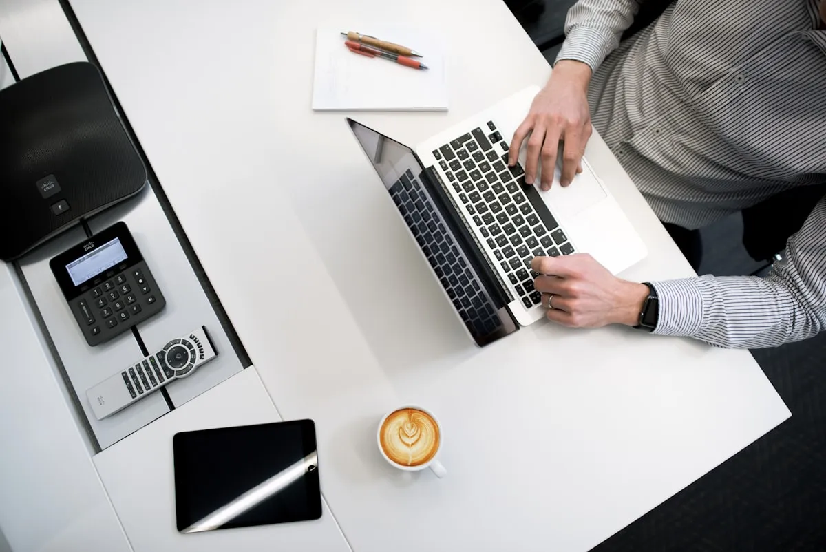 An overhead view of a desk with a laptop, calculator and coffee, set up for finance paperwork