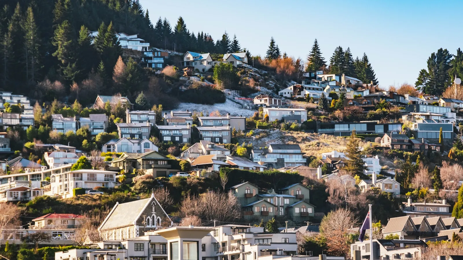 Residential properties on a hillside in Queenstown, New Zealand — representing the milestone of owning your home mortgage-free