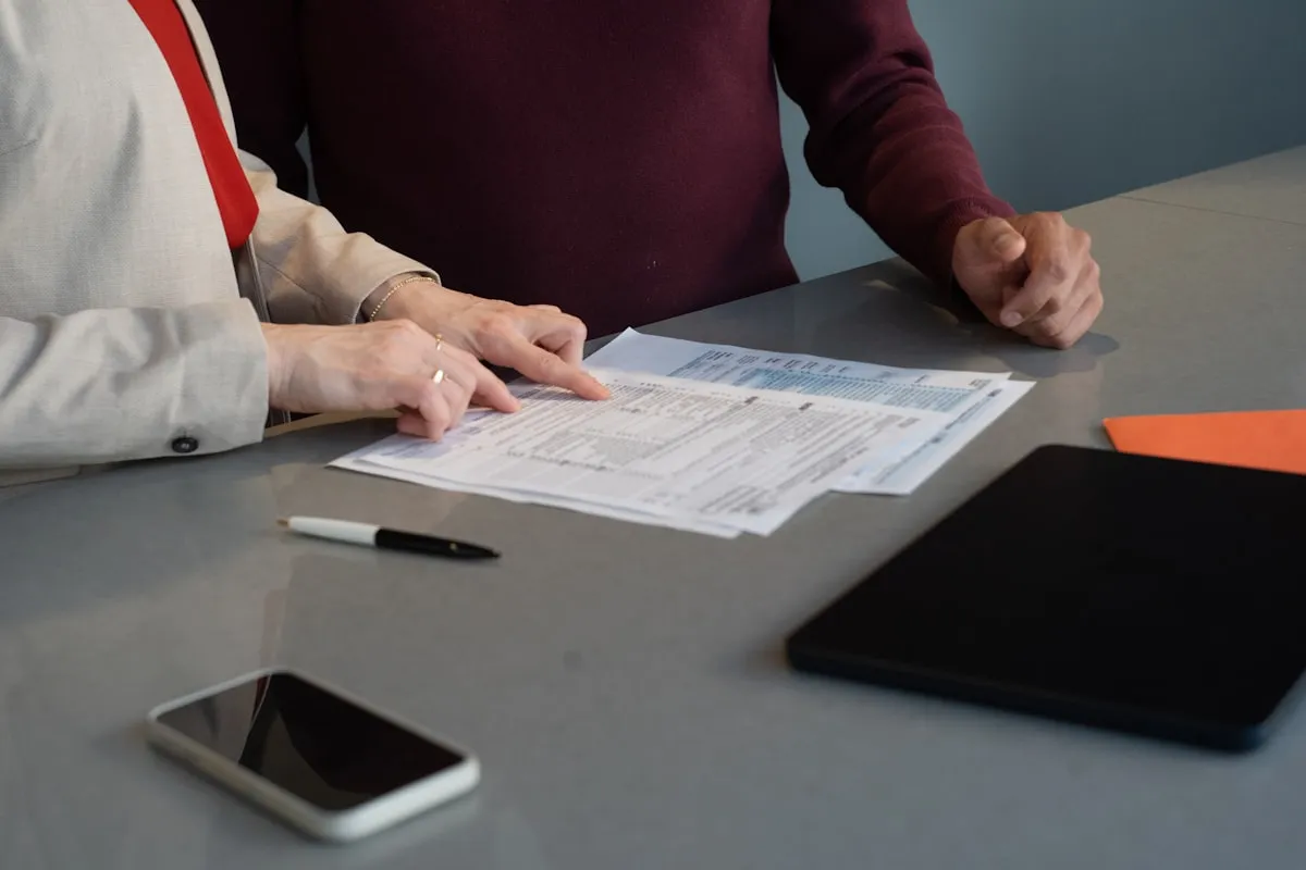 Two people reviewing legal paperwork at a table — lease negotiation before signing a personal guarantee